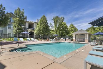 A swimming pool with chairs and umbrellas and a building in the background